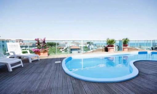 Pool auf einer Terrasse mit Meerblick und Liegestühlen.