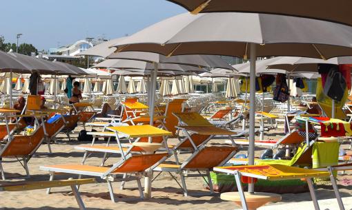 Plage avec des transats orange et des parasols beiges par une journée ensoleillée.